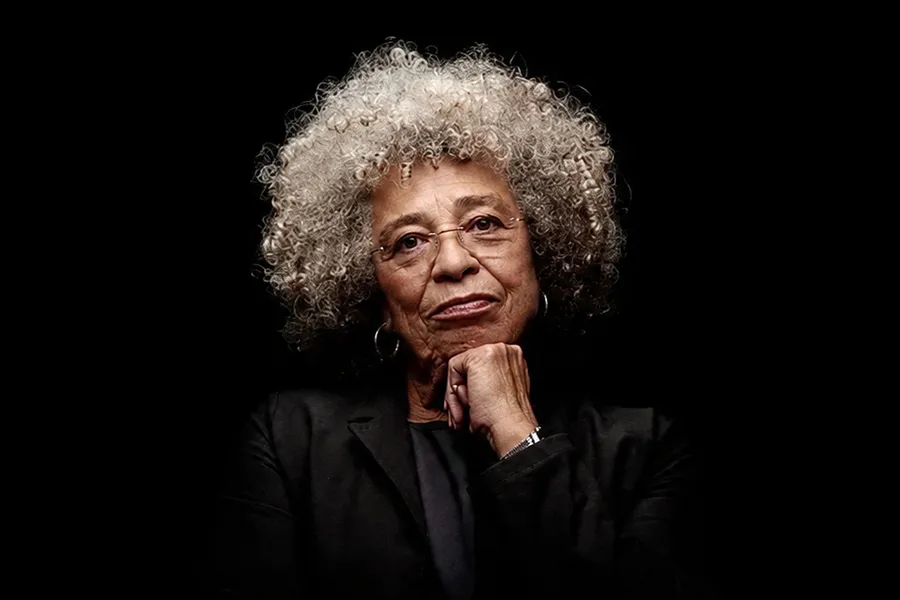 Angela Davis falando em um evento literário, com o público ao fundo