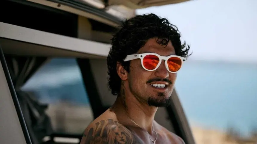 Gabriel Medina usando os óculos inteligentes Oakley Meta HSTN brancos com lentes laranja, à beira-mar